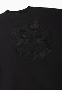 Zwarte sweatshirt met een geborduurd ontwerp van bloemen en vloeiende lijnen op de achterkant. Ribbelboord bij de ronde hals en mouwen.