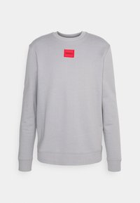 Sudadera gris de mezcla de algodón. Presenta cuello redondo, mangas largas y un parche de logo rectangular rojo en la parte frontal.