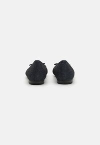 Ballerines pailletées bleu foncé avec un petit talon, bout arrondi et un noeud sur le devant. texture lisse avec une finition brillante.