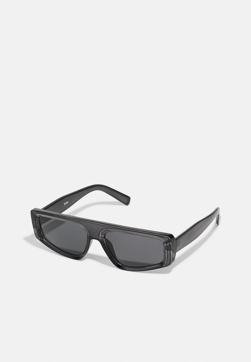Gafas de sol negras rectangulares hechas de plástico grueso, con lentes oscuros y un diseño minimalista con brazos rectos y un sutil logo.