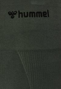 Mørkegrønt tekstureret stof med sort "hummel" logo og stiliseret humlebi-ikon nær toppen i midten.