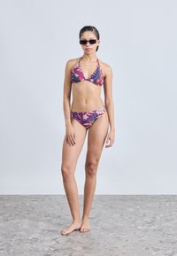 Σετ μπικίνι με πολύχρωμο λουλουδάτο σχέδιο, που αποτελείται από τοπ με λαιμόκοψη halter και σλιπ χαμηλής μέσης, κατασκευασμένο από λεία ύφασμα.