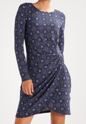 Robe à manches longues en tissu doux et extensible, ornée d'un motif circulaire bleu et blanc, avec un détail froncé sur le côté pour une silhouette galbée.