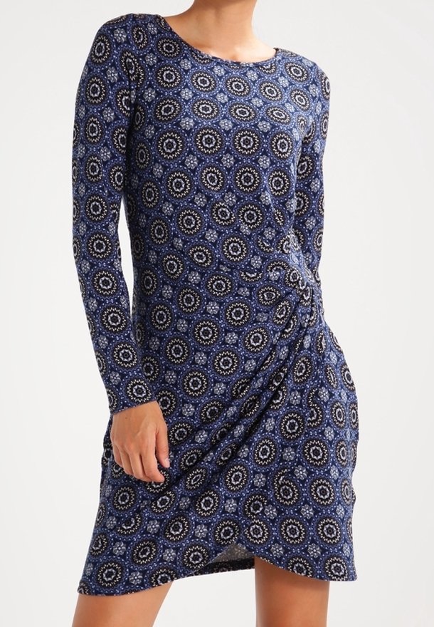 Long-sleeve dress made of soft, stretchy fabric featuring a blue and white circular pattern, with a gathered side detail for shaping.
