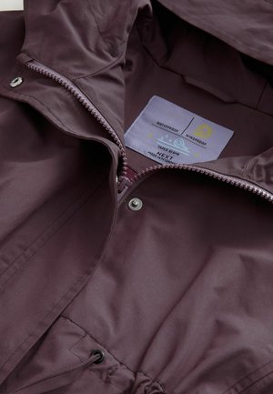 Burgunderfarbene wasserdichte Jacke mit Kapuze, ausgestattet mit einem Frontreißverschluss, versiegelten Nähten, Kordelzug in der Taille und Pflegeetikett im Inneren.