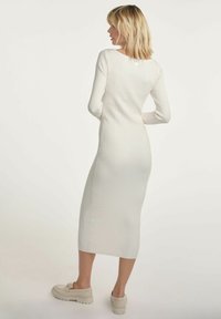 Długa, dopasowana sukienka rybaczka w białym kolorze z długimi rękawami i dekoltem w łódkę. Lekki materiał o gładkiej teksturze, sięgająca do połowy łydki.