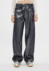 Metalizuotų juodų plačių kojų džinsai, su aukštu liemeniu, priekinėmis kišenėmis ir lygia, blizgia tekstūra. Matomi sidabro detalės.