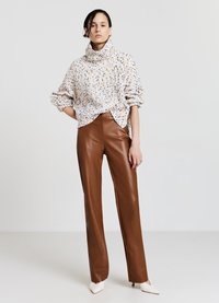 Maglione a collo alto a righe bianche e blu abbinato a pantaloni in pelle marrone aderenti e tacchi bianchi a punta. Texture lisce, vestibilità comoda.