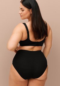 Zwarte bh en hoog opgesneden bikini-broekjes van zacht, glad materiaal met verstelbare bandjes en een naadloos ontwerp, bieden dekking en comfort.
