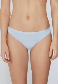 Culotte en coton bleu clair avec une taille fine. Texture lisse, couverture minimale et design sans coutures pour le confort.