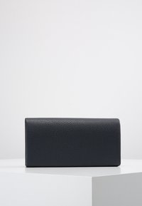 Svart läderclutch med texturerad yta, rektangulär form och en slät stängning. Enkelt design, ingen synlig hårdvara eller accenter.