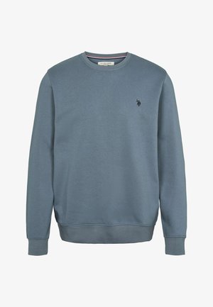 Mėlynas medvilninis džemperis su apvalia iškirpte, ilgomis rankovėmis ir ribbingu ant rankogalių. Kairėje krūtinės pusėje yra mažas juodas logotipas. Lygus paviršius.