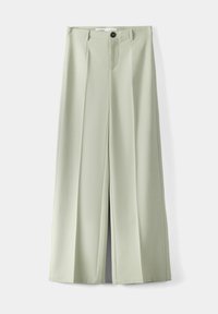 Pantalons larges vert clair avec une texture lisse, présentant des plis avant, une fermeture à bouton unique et une braguette zippée.