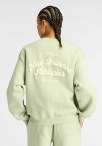 Sweatshirt vert menthe avec un col ras du cou et des poignets côtelés. Présente un texte en relief de couleur crème : "New Balance Athletics" et "Authentic Sportswear."