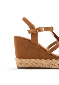 Sandalo con zeppa marrone in suede, con cinturino alla caviglia regolabile e dettagli in juta intrecciata sul tacco a zeppa, con una finitura liscia.
