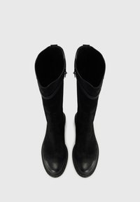 Botas de cuero negro hasta la rodilla con una textura suave, puntera redondeada y cremallera lateral. El diseño presenta un sutil contraste en el material y la costura.