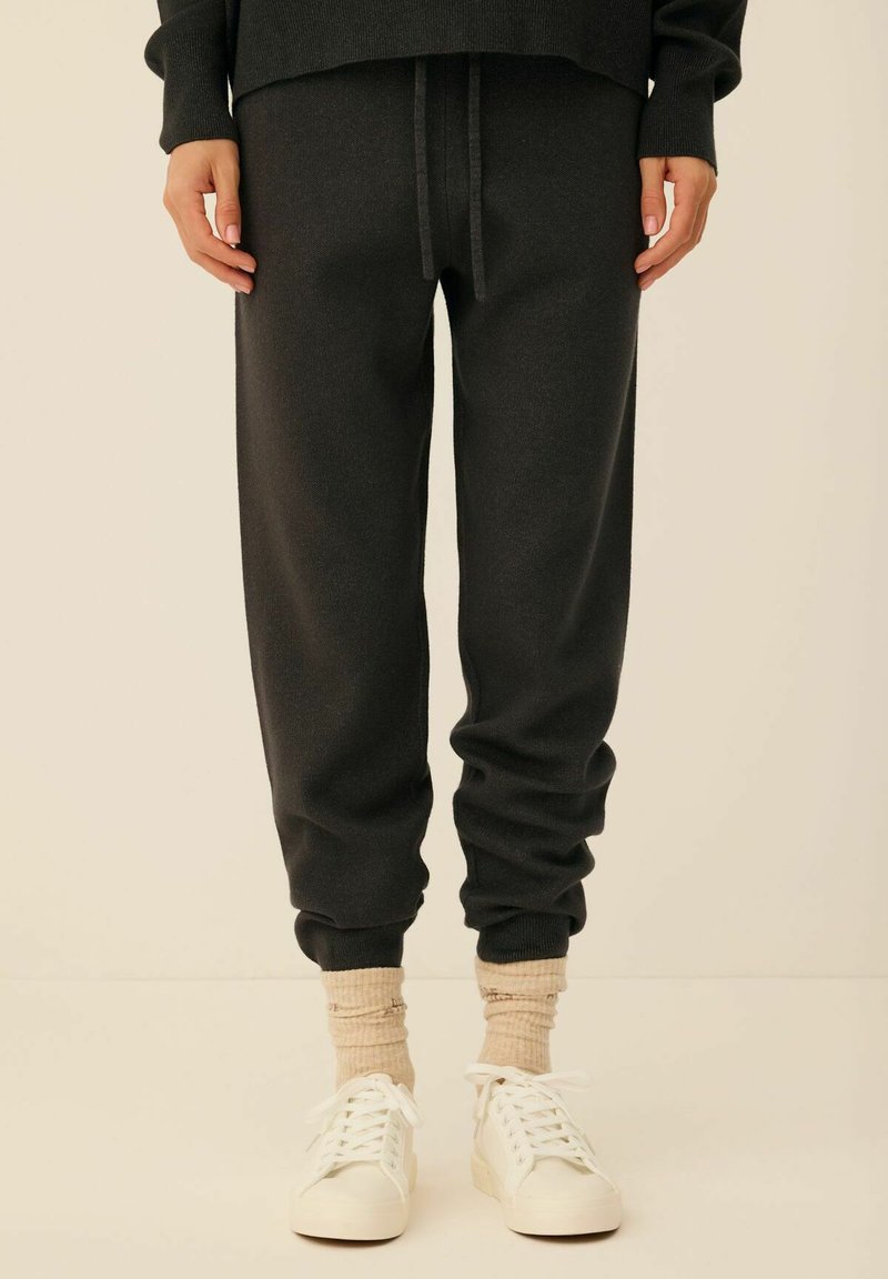 Szare dresy z elastycznym pasem i sznurkiem, z tapered cuffs. Połączone z kremowymi skarpetkami i białymi trampkami.