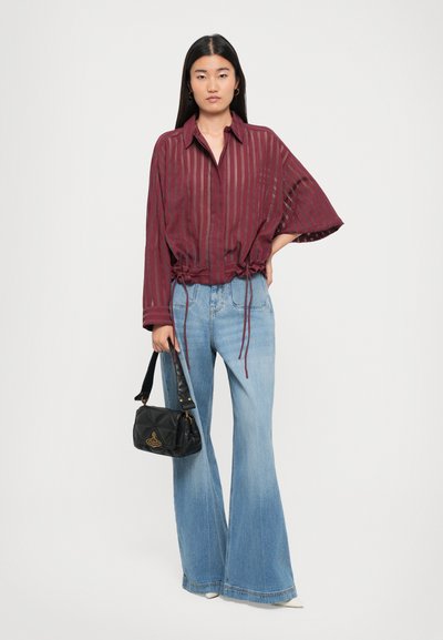 Maroon sheer blouse with vertical stripes, drawstring at the waist, paired with light blue flared jeans and a small black handbag.