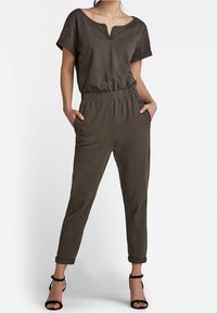 Olijfgroene jumpsuit van zachte stof, met V-hals, korte mouwen, elastische tailleband en zijzakken; taps toelopende pijpen met opgerolde boorden.