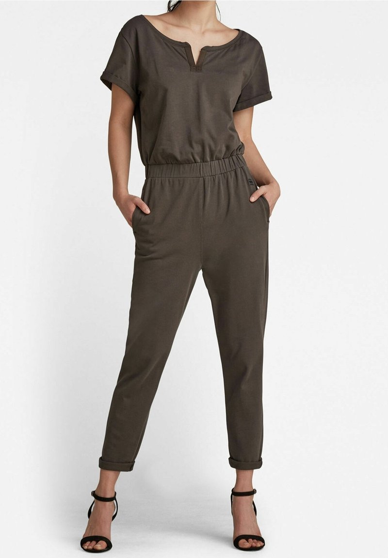 Olijfgroene jumpsuit van zachte stof, met V-hals, korte mouwen, elastische tailleband en zijzakken; taps toelopende pijpen met opgerolde boorden.