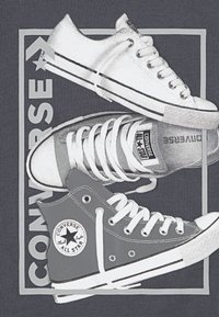 Tre Converse-skor i gråskala: en hög modell med logotyp, en låg modell och en avslappnad slip-on. Mjuk textur, rundade former, kontrasterande skosnören.