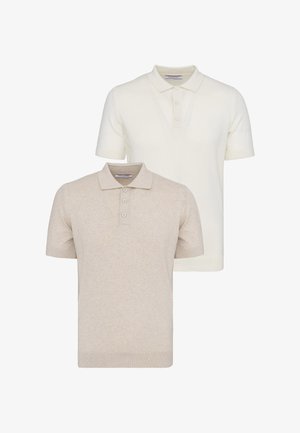 Deux pulls polo à manches courtes, un beige et un blanc cassé, chacun avec un col et trois boutons sur un fond uni.