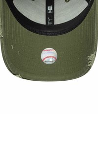 Olivgrüner Hut mit flachem Schirm, ausgestattet mit einer runden Baseballgrafik und roten Nähten. Das Material sieht strukturiert aus und hat einen abgenutzten Rand.