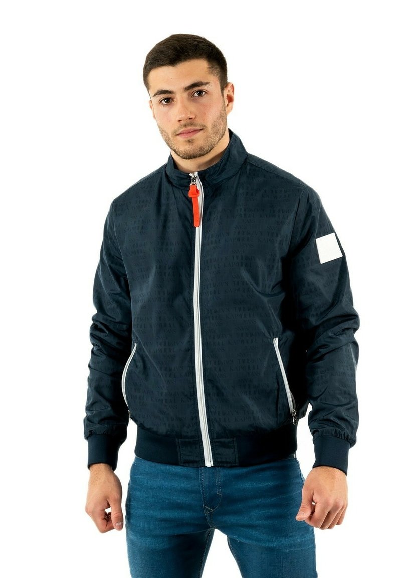 Giubbotto bomber navy con motivo sottile, chiusura frontale con zip, zip arancione a contrasto, polsini a coste e una toppa bianca sul maniche sinistro.