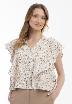 Blusa floreale color crema con maniche a volant e scollatura a V. Presenta piccoli fiori rossi e verdi, tessuto leggero e un design fluido.