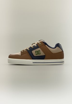 Baskets basses marron, beige et bleu marine avec une semelle blanche et un logo DC vert sur le côté, vues de l'extérieur.