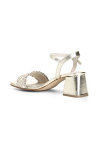 Sandal in oro metallico con design a strisce intrecciate, punta aperta e tacco a blocco. Chiusura alla caviglia a strappo per supporto e facilità d'uso.