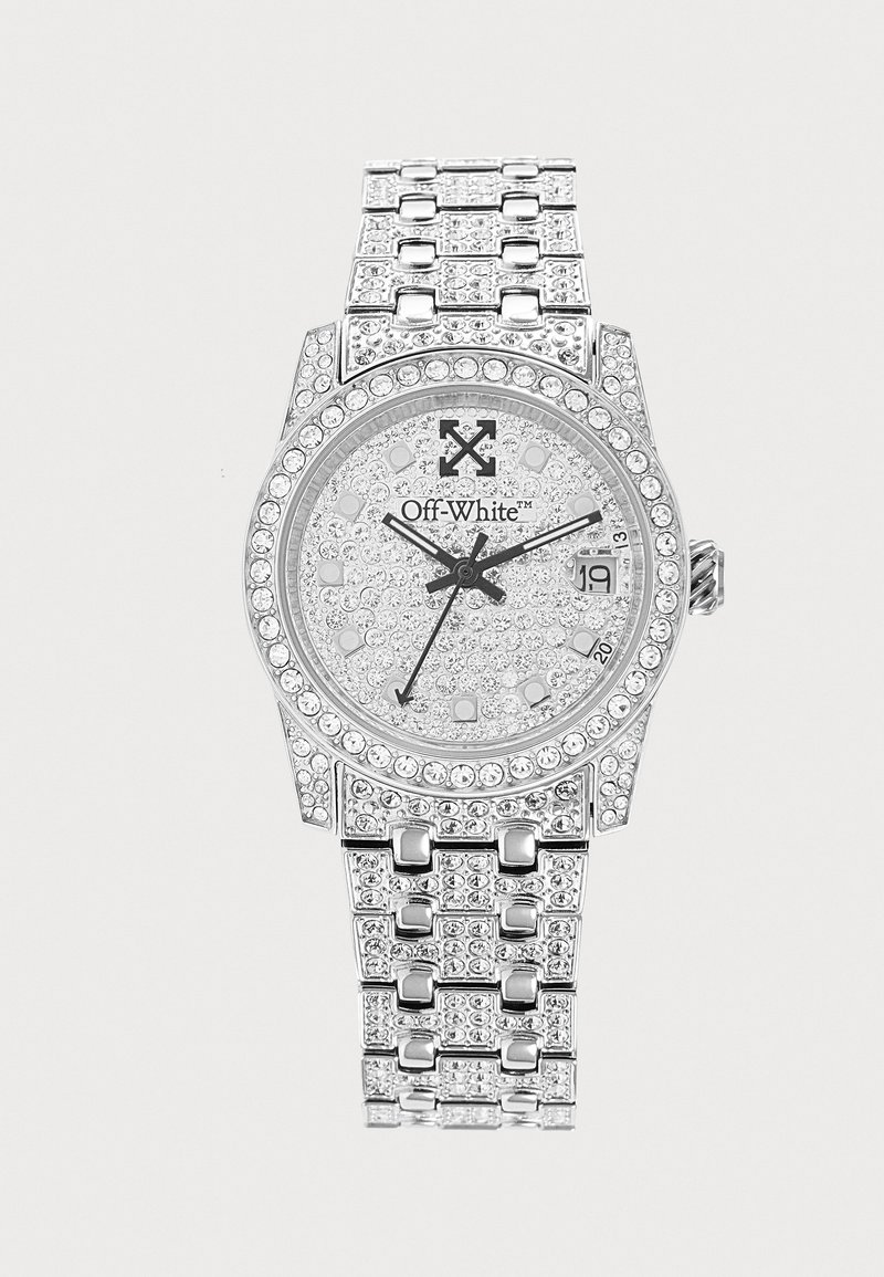 Montre-bracelet de luxe argentée avec ornements en cristal, affichage de la date à 3 heures et marque "Off-White" sur le cadran.