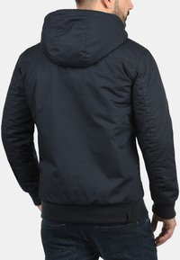 Navy-blauw hoodie met een gladde textuur, elastische boorden en een geribde zoom. Ontworpen met een lichte, relaxte pasvorm.
