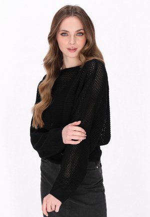 Pulover negru din tricot cu o croială lejeră, design cu țesătură deschisă, mâneci late și manșete cu nervuri, asortat cu o fustă din denim întunecat.