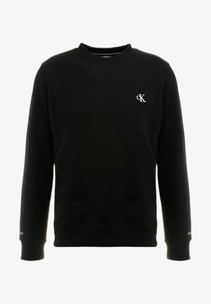 Juodas medvilninis džemperis su apvaliu kaklu, raukšlėtais rankogaliais ir apačia, su mažuoju baltu "cK" logotipu kairėje krūtinės pusėje.