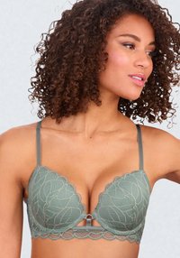 Le bralette en dentelle verte présente des bords festonnés, un décolleté plongeant et de fines bretelles réglables avec un détail en trou de serrure à l'avant.