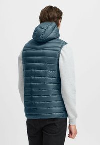 Chaleco acolchado con capucha para hombre en tono azul verdoso, con un diseño de acolchado horizontal, un acabado ligero y mangas de sudadera en gris contrastante.