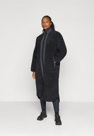 Lange zwarte fleece jas met een opstaande kraag en een rits aan de voorkant, voorzien van twee zijzakken en een textuurafwerking.