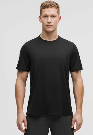 Schwarzes T-Shirt mit kurzen Ärmeln, aus weichem, glattem Stoff, mit rundem Halsausschnitt und lockerer Passform, geeignet für Freizeit- oder Sportbekleidung.