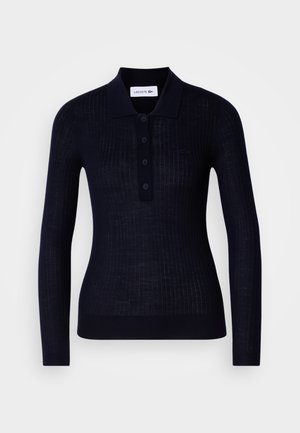 Polo en laine à manches longues de couleur marine avec texture côtelée, patte de boutonnage à trois boutons et col replié. Présente un petit logo sur la poitrine.