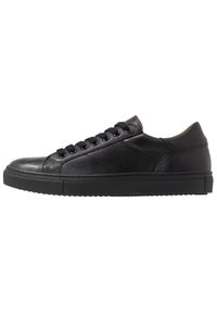 Czarne niskie skórzane sneakersy z czarnymi sznurowadłami, gumową podeszwą i subtelnymi detalami zszycia, pokazane od zewnętrznej strony.