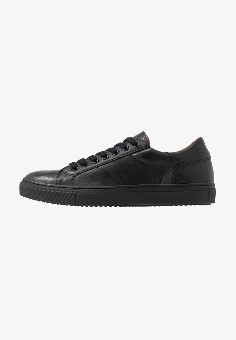 Czarne niskie skórzane sneakersy z czarnymi sznurowadłami, gumową podeszwą i subtelnymi detalami zszycia, pokazane od zewnętrznej strony.