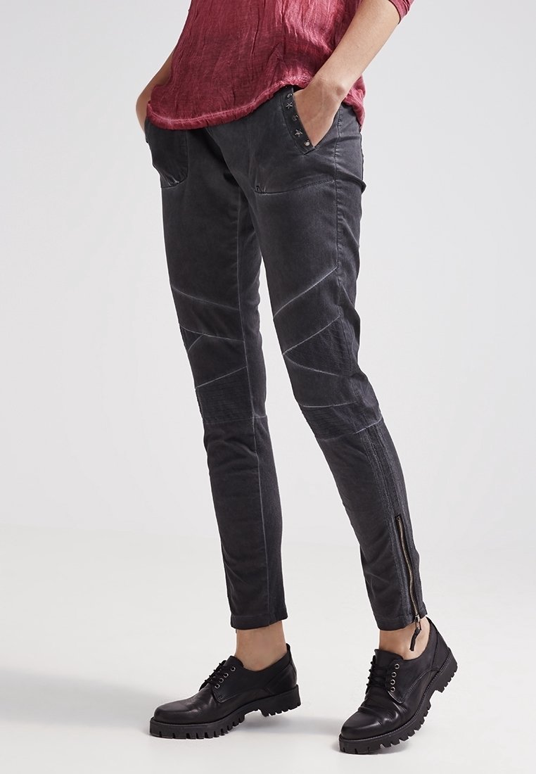 Donkergrijze skinny broek met contrasterende stiksels, zijzakken en ritsen bij de enkels. Gemaakt van duurzame stof met een gladde textuur.