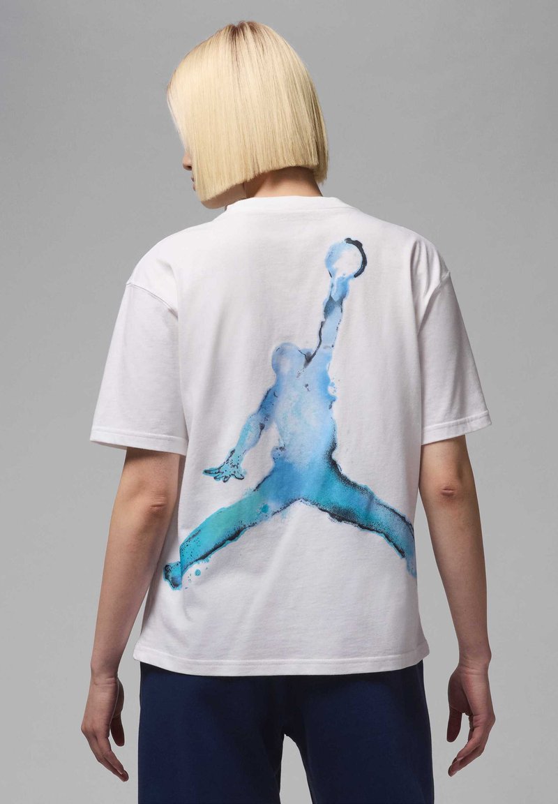 Camiseta de algodón blanca con un diseño de salpicadura azul de un jugador de baloncesto en la parte posterior, con cuello redondo y mangas cortas.
