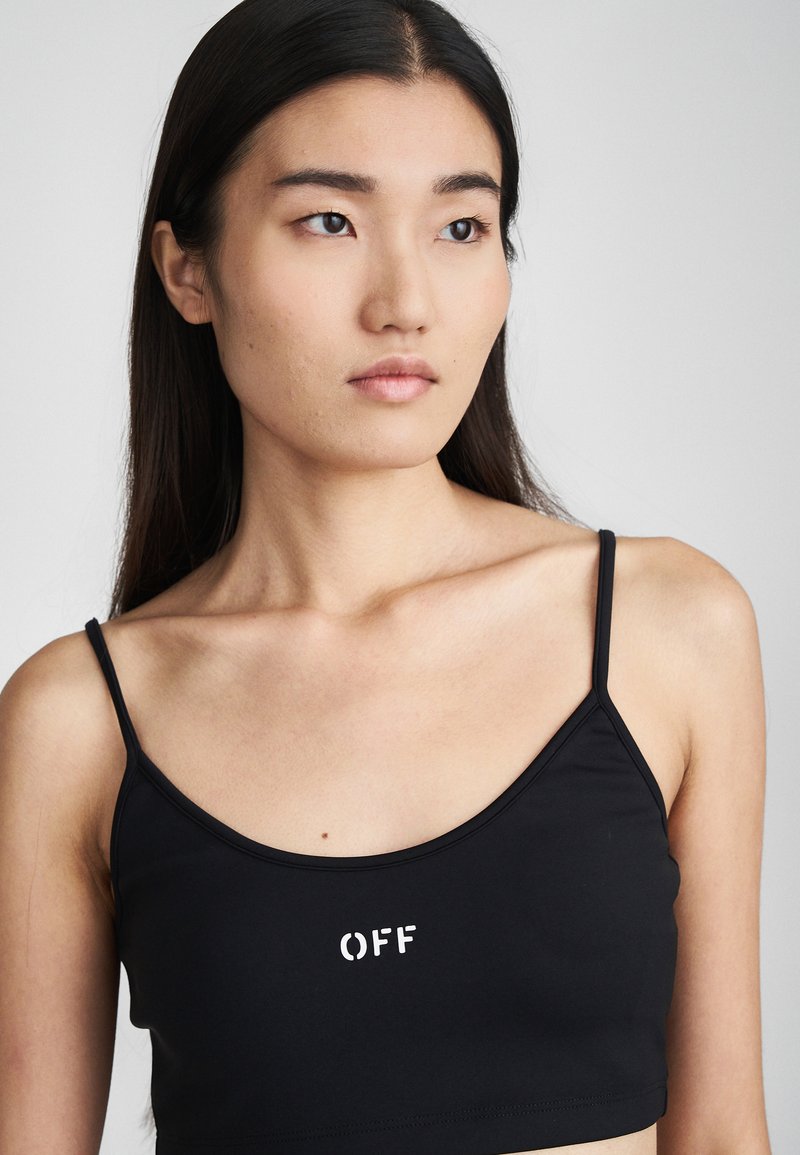 Černý crop top s tenkými ramínky a kulatým výstřihem. Na přední straně se nachází bílé logo "OFF". Vyrobeno z hladkého, elastického materiálu.