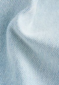 Lysblå denimstof med en fin twill-vævning og subtile kontrasterende tråde, der skaber en tekstureret overflade med en blød fald.