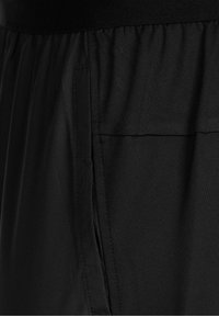 Gros plan sur un tissu noir avec une poche rectangulaire et des coutures visibles, mettant en valeur la texture et les détails des coutures.