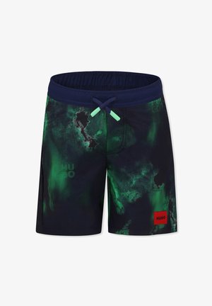 Bañador en un azul marino oscuro con patrones abstractos verdes. Cuenta con una cintura elástica, cordones y un parche rojo con el logo.