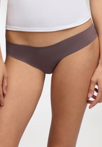 Bikini breve e senza cuciture in un morbido colore malva, realizzato in un materiale liscio ed elastico. Caratterizzato da una cintura larga e da una copertura minima.