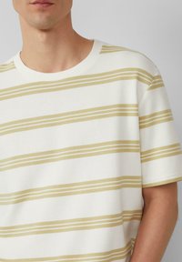 Witte t-shirt met korte mouwen en horizontale gele strepen, met een ribbelstructuur en een ronde hals.